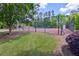 Tennis court behind a chain link fence with fresh green grass and colorful bushes at 2951 Edgewater St, South Fulton, GA 30331