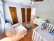 Cozy Bedroom featuring a white crib, soft armchair, and natural wood flooring in a neutral color palette at 3205 Brandywine Nw Pl, Marietta, GA 30064