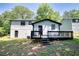 Backyard view of a two-story home with a deck, surrounded by lush greenery and mature trees at 3959 Wood Path Dr, Stone Mountain, GA 30083