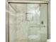 Modern walk-in shower featuring marble-look tile, built-in niche, bench and clear glass doors at 3959 Wood Path Dr, Stone Mountain, GA 30083