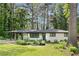 Charming white brick home featuring a bright teal front door, lush lawn, and mature trees at 2425 Clifton Springs Rd, Decatur, GA 30034