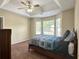 Bedroom with a tray ceiling, ceiling fan, and large windows overlooking the front yard at 6940 Treeline Dr, Cumming, GA 30028