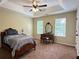 Bedroom featuring a tray ceiling, ceiling fan, and windows overlooking the side yard at 6940 Treeline Dr, Cumming, GA 30028