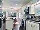Bright kitchen features granite counters, stainless steel appliances, mosaic backsplash, hardwood floors and island seating at 6940 Treeline Dr, Cumming, GA 30028