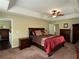 Spacious main bedroom featuring a tray ceiling, a ceiling fan, and dark wood furniture at 6940 Treeline Dr, Cumming, GA 30028