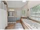 Bright bathroom showcases a tiled soaking tub with multiple windows for natural light, a dual sink and a skylight at 1172 Malvern Hunt Ct, Lawrenceville, GA 30043