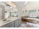 Well-lit bathroom featuring dual sinks, a large mirror, and a soaking tub with natural light from the skylight and windows at 1172 Malvern Hunt Ct, Lawrenceville, GA 30043