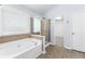 Modern bathroom with a soaking tub, glass-enclosed shower, and window with blinds for privacy at 1310 Scenic View Trce, Lawrenceville, GA 30044