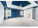 Large bedroom with striking blue accent wall, tray ceiling, plush carpet, and abundant natural light from windows at 1310 Scenic View Trce, Lawrenceville, GA 30044