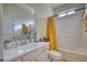 A bright bathroom with vanity, toilet, and bathtub; the tub has a bright yellow curtain for privacy at 4180 Mount Paran Dr, Social Circle, GA 30025