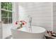 Elegant bathroom featuring a freestanding tub, shiplap walls, and a window offering natural light at 400 N Peachtree Pkwy, Peachtree City, GA 30269