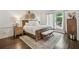 Bright main bedroom with a rustic bed and bench that open up to a porch at 400 N Peachtree Pkwy, Peachtree City, GA 30269