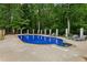 Stunning pool with blue tile, stone surround, and lounge chairs in a private wooded backyard at 400 N Peachtree Pkwy, Peachtree City, GA 30269