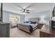 This bedroom features a tufted headboard, a ceiling fan, neutral carpet, and natural light from the windows at 704 Woodbridge Dr, Woodstock, GA 30188