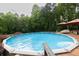Refreshing above-ground pool with deck, patio furniture, and landscaping, surrounded by trees at 814 Clarke Trl, Dacula, GA 30019