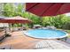 Inviting pool area with a large deck, umbrellas, patio furniture, and a view of the wooded backyard at 814 Clarke Trl, Dacula, GA 30019