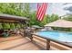 Poolside view showcasing deck, outdoor dining, an American flag, and mature trees at 814 Clarke Trl, Dacula, GA 30019