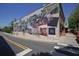 Large, vibrant mural showcasing local history and culture, located on the side of a building at 110 Barnesdale Ter, Woodstock, GA 30188