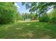 A grassy field with a small home, red barn, and mature trees in the background at 110 Barnesdale Ter, Woodstock, GA 30188