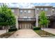 Rear exterior view of brown townhome featuring a two-car garage and second story deck at 3585 Adelaide Xing, Brookhaven, GA 30319