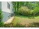 Side view of a home's backyard featuring a concrete walkway and verdant landscaping at 3698 Fairlane Nw Dr, Atlanta, GA 30331