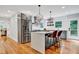 Bright kitchen area with white island, stainless steel fridge, modern light fixtures and hardwood floors at 1571 Boulevard Lorraine Sw, Atlanta, GA 30311