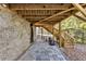 View of a stone patio and storage area with stairs leading to the upper deck, wood beams are on the ceiling at 1571 Boulevard Lorraine Sw, Atlanta, GA 30311
