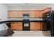 This kitchen features granite counters, wooden cabinets, tile backsplash, and black appliances at 3453 Dianthus Ln, Lawrenceville, GA 30044