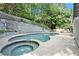 The backyard includes a pool and spa tub bordered by a rock retaining wall and landscaped greenery at 6300 Mountain Brook Ln, Atlanta, GA 30328