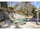The backyard includes a pool and spa tub bordered by a rock retaining wall and mature trees at 6300 Mountain Brook Ln, Atlanta, GA 30328