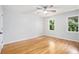 Well-lit bedroom featuring hardwood floors, a ceiling fan, and two windows with tree views at 6300 Mountain Brook Ln, Atlanta, GA 30328