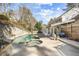 Backyard view of uniquely shaped pool and attached hot tub, with stone retaining wall and mature trees at 6300 Mountain Brook Ln, Atlanta, GA 30328