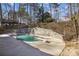 Backyard pool area featuring a diving board, hot tub, stone retaining wall, and lush landscaping at 6300 Mountain Brook Ln, Atlanta, GA 30328