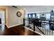 Upstairs hallway featuring hardwood flooring, black railing, and an open view to the living room at 133 Canal St, Hampton, GA 30228