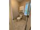 Small half-bath with toilet, cabinet, and window at 1502 La Fayette Pl, Loganville, GA 30052