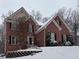 Brick two-story home with snow-covered front yard and mature trees in a winter setting at 1502 La Fayette Pl, Loganville, GA 30052