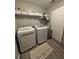 Functional laundry room featuring a washer, dryer, shelving, and stylish decor at 1502 La Fayette Pl, Loganville, GA 30052
