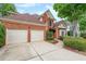 Lovely traditional brick home boasts an attached garage, wide driveway, and manicured front lawn with mature trees at 1996 Wellesley Trce, Atlanta, GA 30338