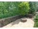 Stone patio featuring a stone fire pit and fenced yard backing to mature trees at 7520 Ledgewood Way, Suwanee, GA 30024