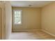 Bright bedroom with neutral walls and carpet, featuring a window and natural light at 7520 Ledgewood Way, Suwanee, GA 30024