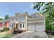 Elegant home featuring a red front door, second story balcony, manicured lawn, beautiful flowerbeds and an attached two-car garage at 7520 Ledgewood Way, Suwanee, GA 30024