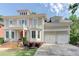 Two-story home with a red front door, balcony, manicured lawn, beautiful flowerbeds and an attached two-car garage at 7520 Ledgewood Way, Suwanee, GA 30024