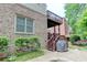 Back of brick house with wood stairs leading to a covered deck, stone patio, and green landscaping at 7520 Ledgewood Way, Suwanee, GA 30024