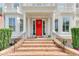 Inviting front entrance features a red door, brick steps, iron railings, and manicured greenery at 7520 Ledgewood Way, Suwanee, GA 30024