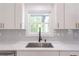 A close-up view of the kitchen sink with marble countertops, white cabinets, and stylish hardware at 2265 Hillbriar Dr, Buford, GA 30518