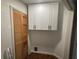 Practical laundry area with wooden slat door and white upper cabinets providing efficient storage solutions at 3050 Camden Way, Alpharetta, GA 30005