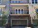A two car garage with a balcony above and brick columns supporting the structure at 1616 Avery Way, Tucker, GA 30084