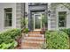 Home's front entrance features a gray painted door, brick stairs, decorative plants, and modern sconces at 2680 Spalding Dr, Atlanta, GA 30350