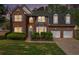 Evening shot of a brick two-story home, showcasing illuminated windows and manicured landscaping at 4535 Howell Farms Nw Rd, Acworth, GA 30101