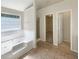 Bright bathroom featuring tile floors, large soaking tub, walk-in shower and doorway to large closet at 6260 Selborn Sw Dr, Atlanta, GA 30331